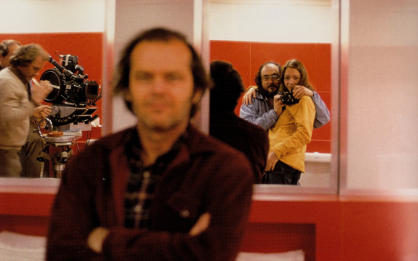 Stanley Kubrick e la figlia Vivian si fotografano davanti ad uno specchio sul set di Shining. In primo piano, uno sfocato Jack Nicholson.